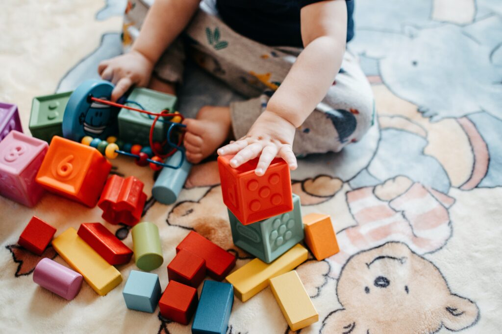 A baby stacking brightly colored blocks on top of each other.